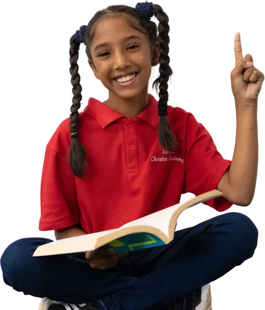 A smiling SCA learner sitting with an open book and pointing up