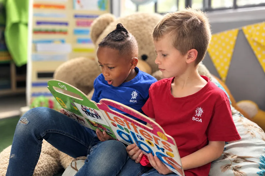 Two learners reading a picture book together in the reading corner