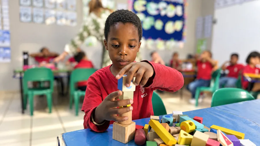 A young learner building a tower with wooden blocks